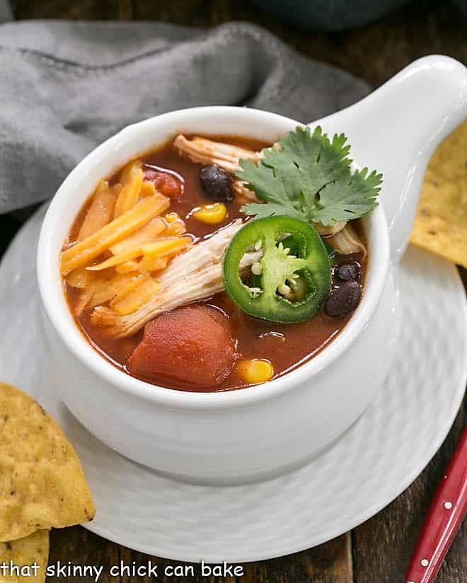 Slow Cooker Chicken Enchilada Soup in a soup bowl on a white plate.