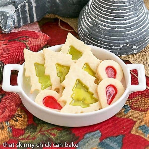 Stained glass cookies in a white dish on a red cloth.