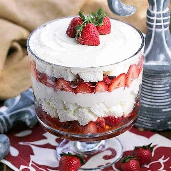Strawberry Cheesecake Trifle in a glass trifle bowl topped with 3 whole strawberries.