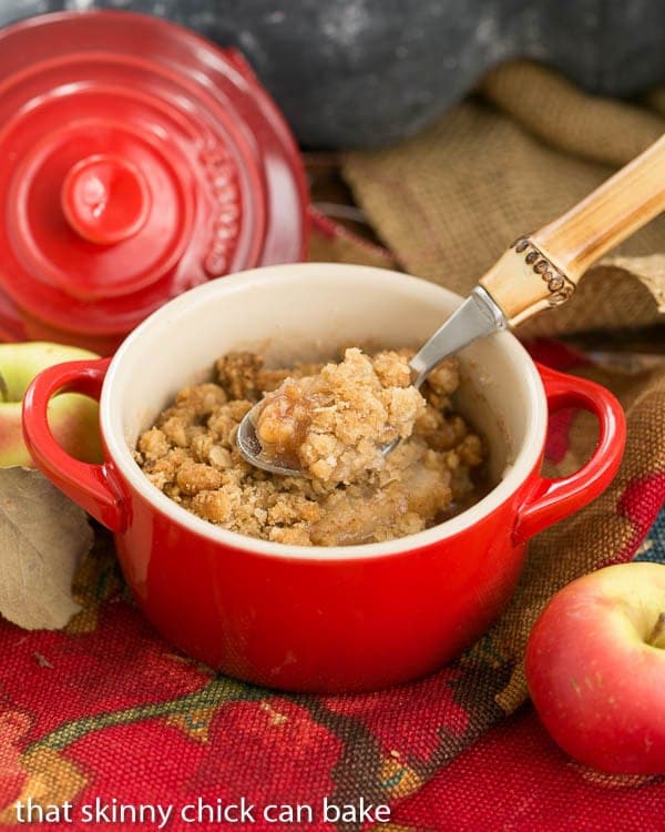 Apple Pear Crisp in a red ramekin with a bamboo handle spoon.