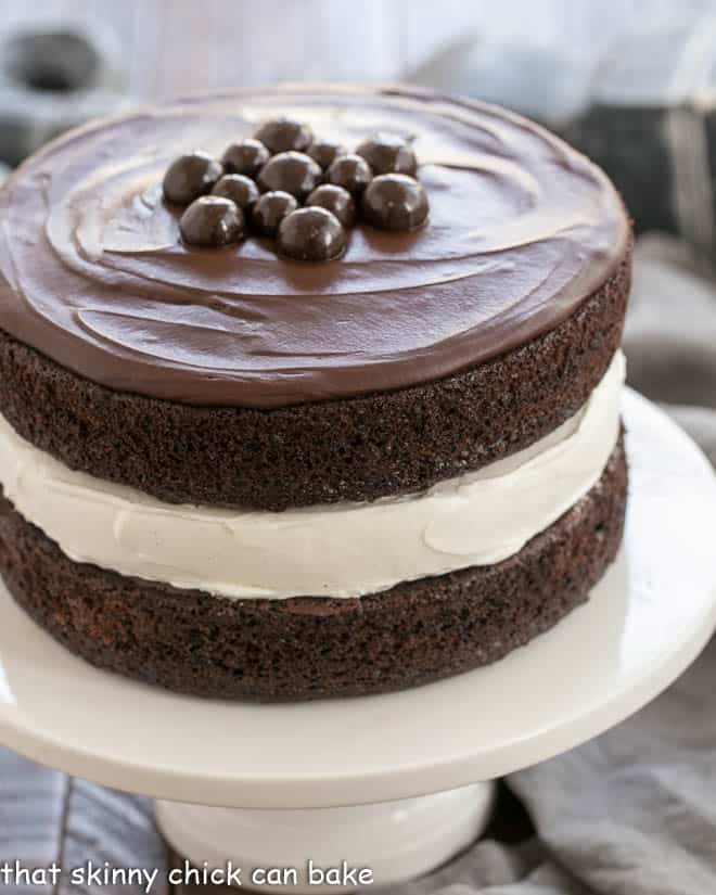 Ding Dong Cake topped with chocolate candies on a white cake stand.