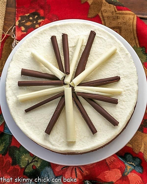 Overhead view of a beautiful white chocolate and milk chocolate Layered Mousse Cake on a white cake plate.