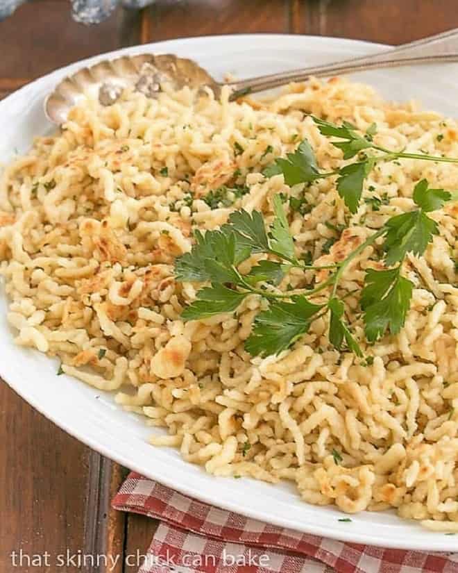 Spaetzel topped with parsley sprig on a white platter.