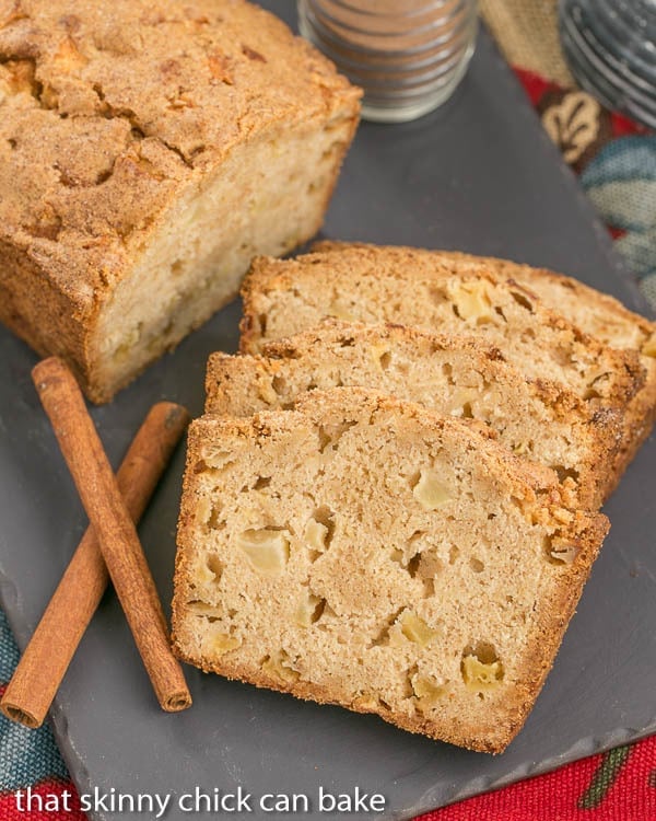 Apple Bread - This moist, cinnamon spiced bread is perfect for snacking, breakfast or brunch! Cinnamon Spiced Apple Bread slices and a partial loaf on a slate tray.