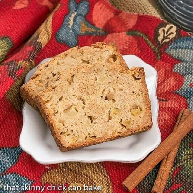 Slices of Apple Bread on a white plate with cinnamon sticks.