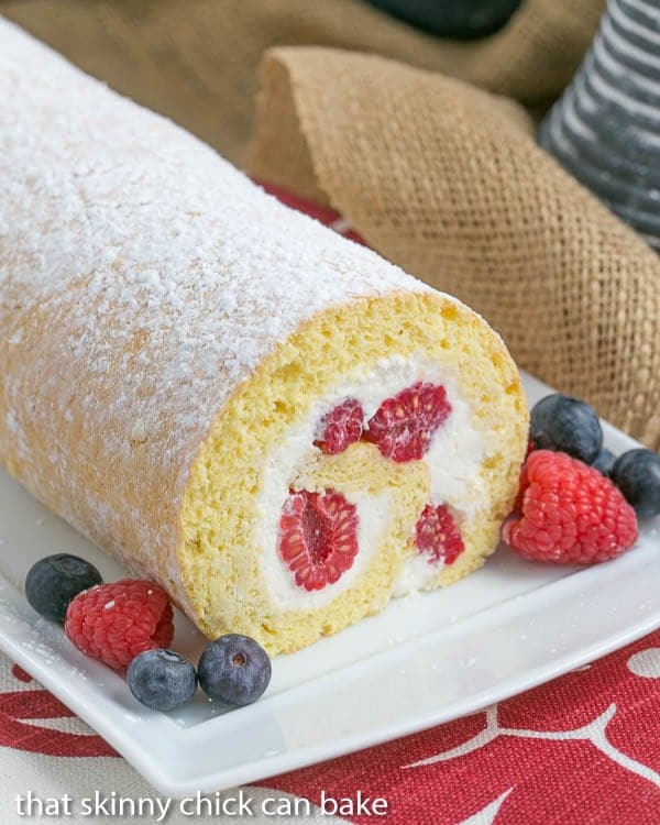 Berry Roulade on a white serving tray with a garnish of fresh berries