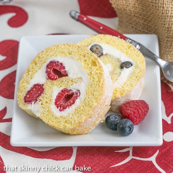 Slices of Berry Roulade on a square white plate with fresh berries to garnish