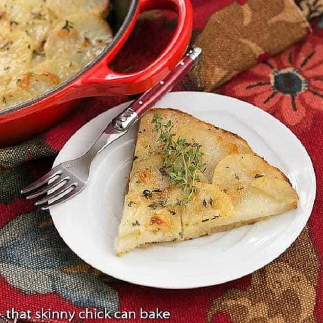 Slice of Cheesy Potato Galette on a white plate with a red handled fork
