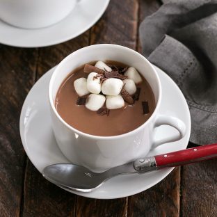 Ciaoccolate Calda in a white ceramic cup on a saucer with a red handled spoon and marshmallow garnish
