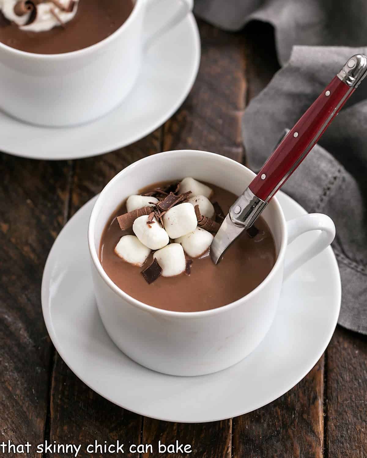 Thick Italian hot chocolate in a white coffee cup with a red handle spoon inserted.