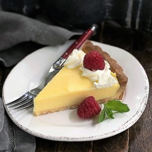 Creamy Lemon Tart slice garnished with raspberries and cream
