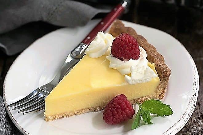 Creamy Lemon Tart slice garnished with raspberries and cream
