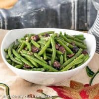 Side view of mustard green beans in a white serving bowl