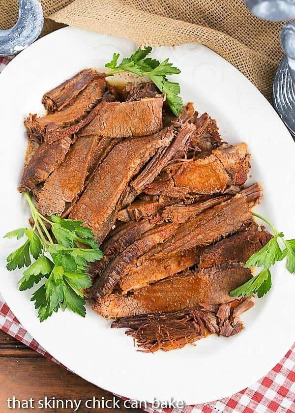 white serving platter filled with slices of Oven Braised Texas Brisket 