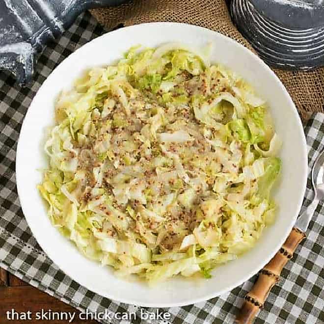 a plate of Sauteed Cabbage with Mustard and a serving spoon on the side of the dish.