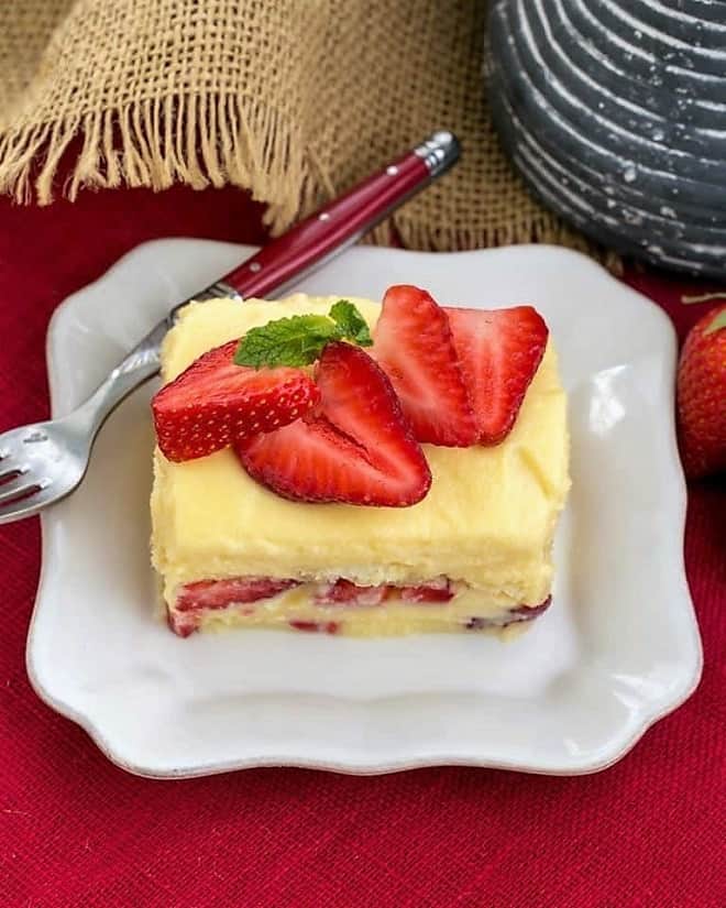 Berry Tiramisu with Grand Marnier garnished with fresh strawberries on a square white plate.