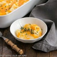 A serving of cheesy potato casserole in a round dish with a bamboo handle fork