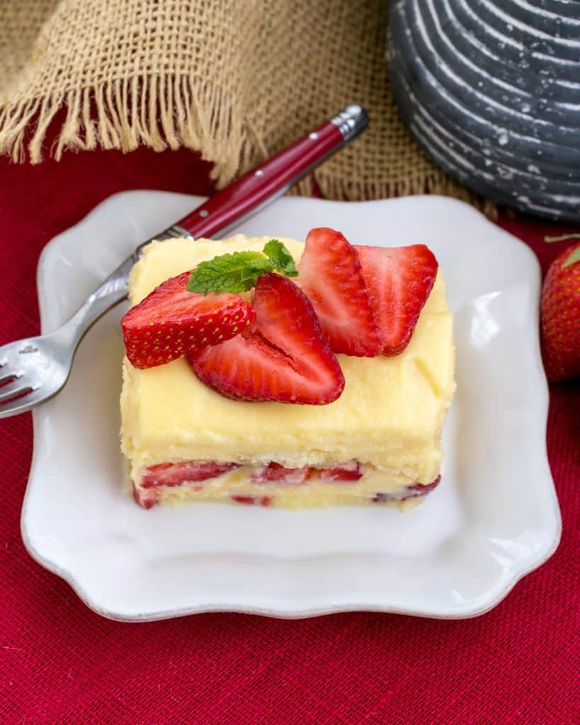 Berry Tiramisu with Grand Marnier slice on a square white plate with a red handled fork