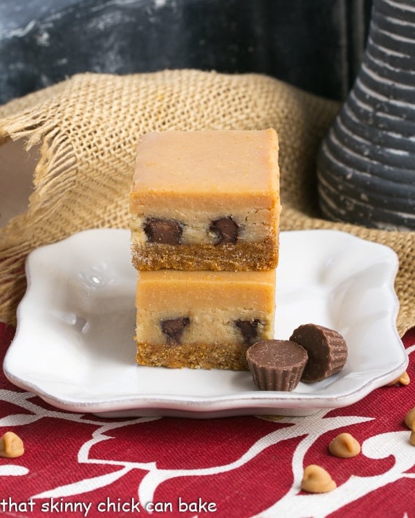Peanut Butter Cheesecake Bars stacked on a square white dessert plate
