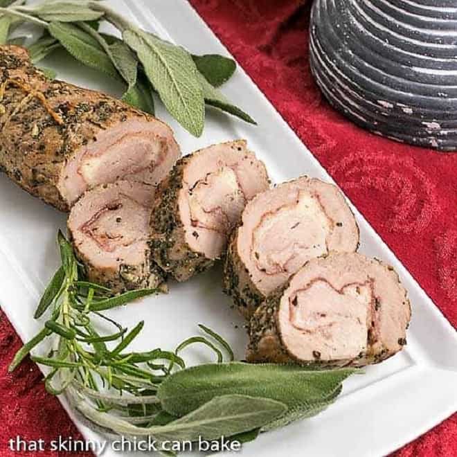 Prosciutto and Pork Pinwheels on a white tray garnished with herbs