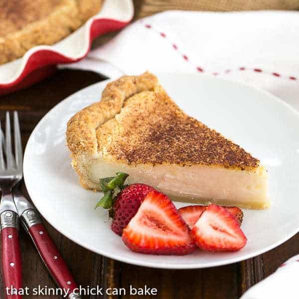 A slice of Hoosier Sugar Cream Pie on a white plate with strawberry slices.