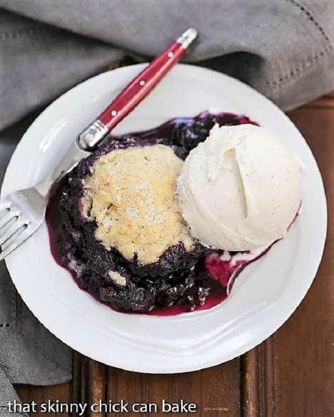 Grilled Blueberry Cobbler a la mode on a white plate with a red handled fork.