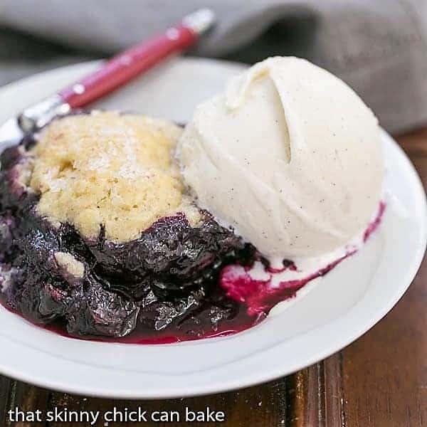 Grilled Blueberry Cobbler on a white dessert plate topped with a scoop of ice cream.