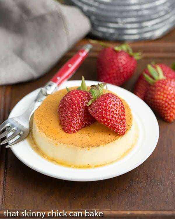 Mini vanilla Flans on a white dessert plate with a red handled fork