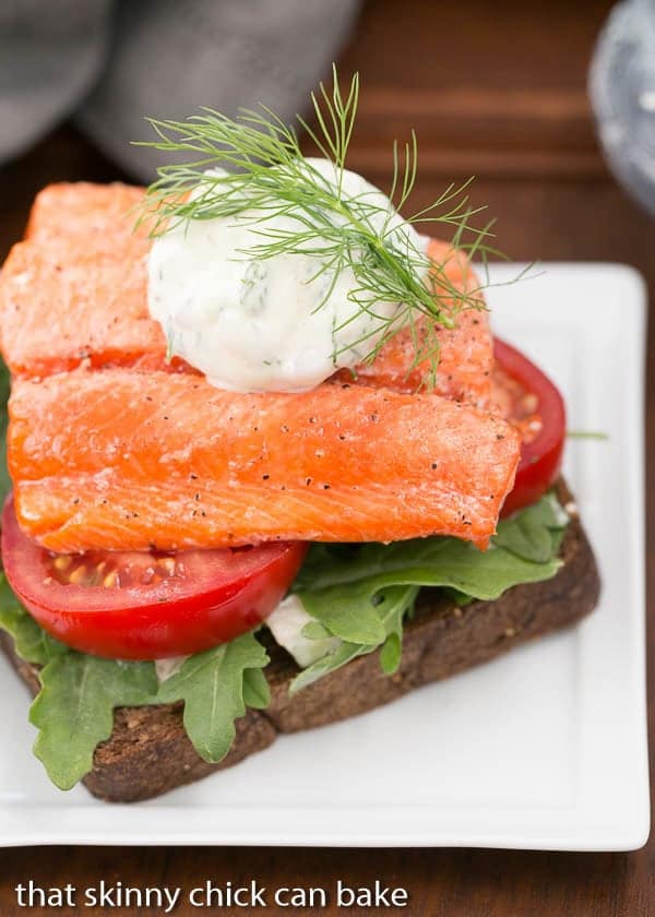 Open-Faced Salmon Sandwiches with Herb Cucumber Relish on a square white plate with a dollop of relish and dill sprig to garnish