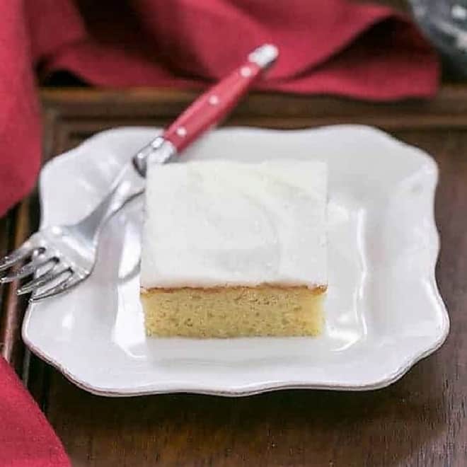 Slice of white sheet cake with a red handled fork.