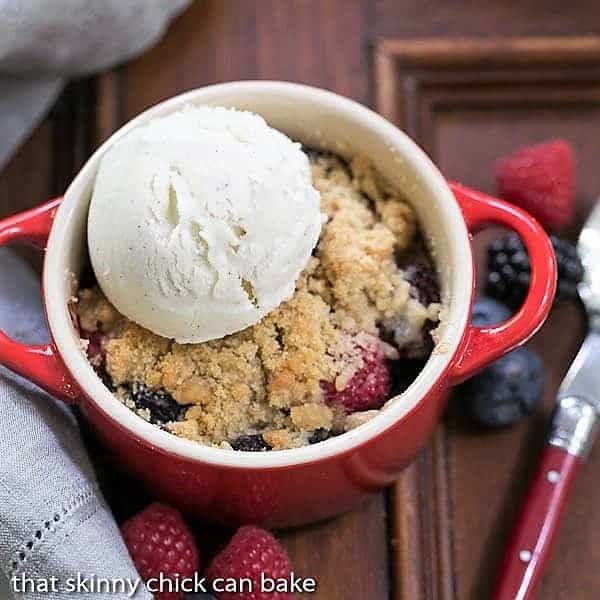 overhead view of a berry crisp siwht a scoop of vanilla ice cream in a small red ramekin