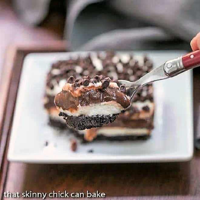 Forkful of Chocolate Lasagna| in front of a slice on a square white plate