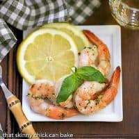 Grilled Shrimp Scampi on a square white plate with basil and lemon slices