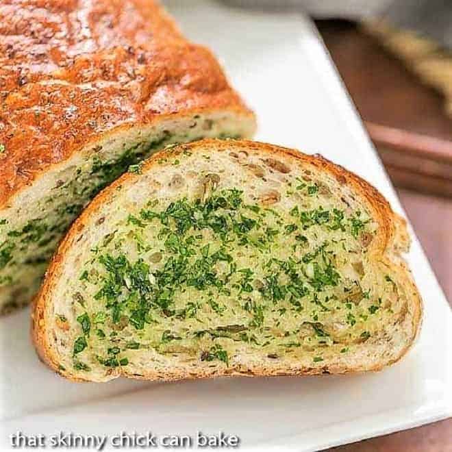 Herb Garlic Bread slice next to loaf on a white platter