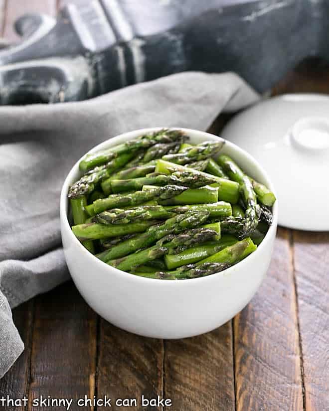 Oven roasted asparagus with balsamic brown butter in a white ceramic bowl.