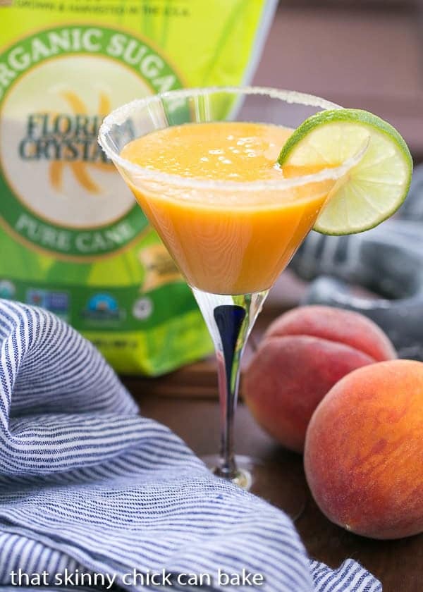 Peach Margaritas in a martini glass garnished with a slice of lime.