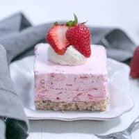 A slice of mile high strawberry pie on a square dessert plate