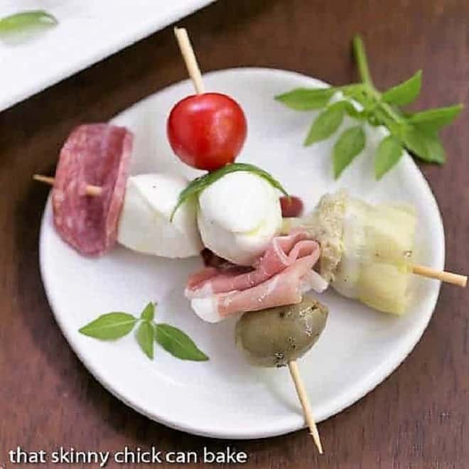 Antipasto Skewers crossed on a round white plate.