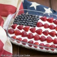 Berry Cheesecake Flag Dessert in a pyrex dish topped with blueberry and strawberry stars and stripes
