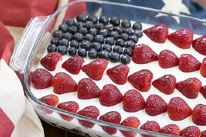 Berry Cheesecake Flag Dessert in a pyrex dish topped with blueberry and strawberry stars and stripes