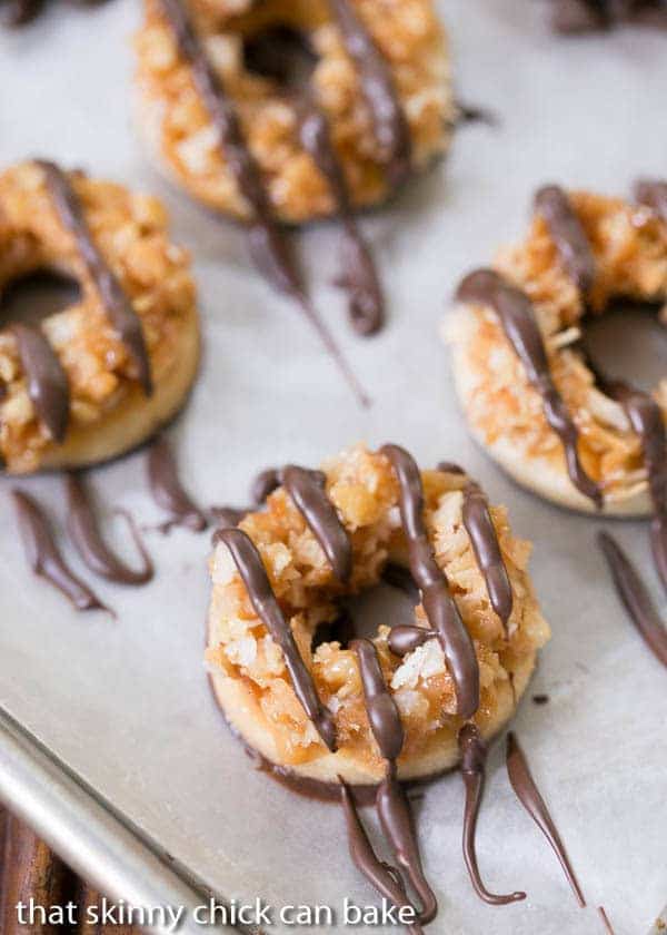 The BEST Homemade Samoa Cookies Recipe -These exquisite creations are heads and tails better than the originals! Homemade Samoa Cookies with a drizzle of chocolate on a sheetpan.