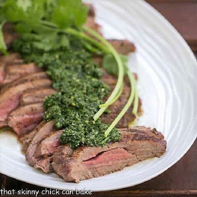 Close view of Grilled Flank Steak with Chimichurri Sauce on a white oval platter.