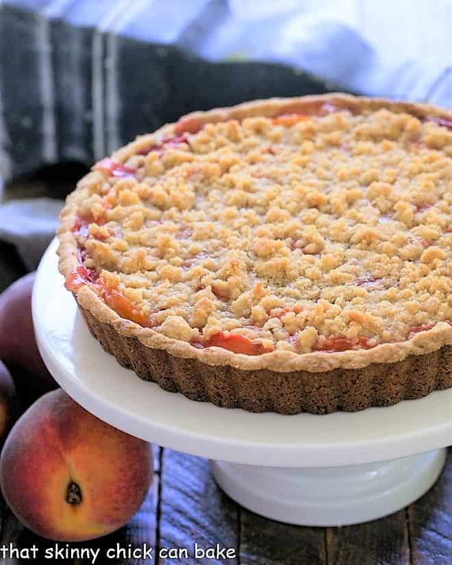 Streusel Topped Peach Tart on a white ceramic cake stand.