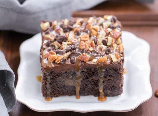 Turtle Poke Cake | A marvelous chocolate cake infused with caramel and topped with buttercream, pecans and chocolate chips!