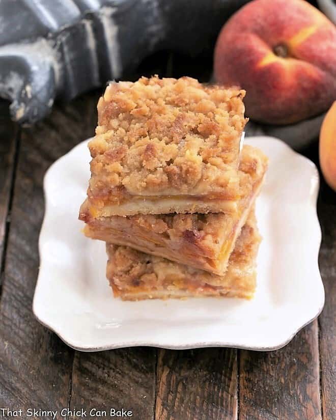 3 peach pie bars stacked on a square white plate