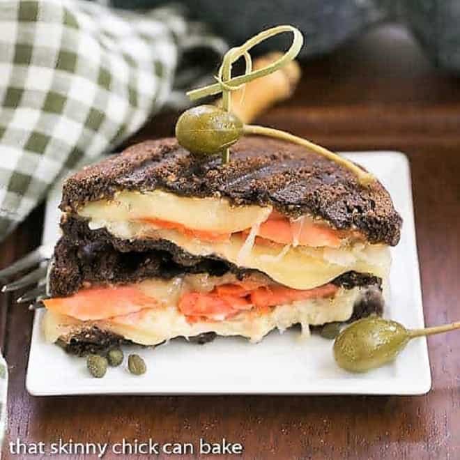 Smoked Salmon Reuben Sandwich cut in half and stacked on a white plate.