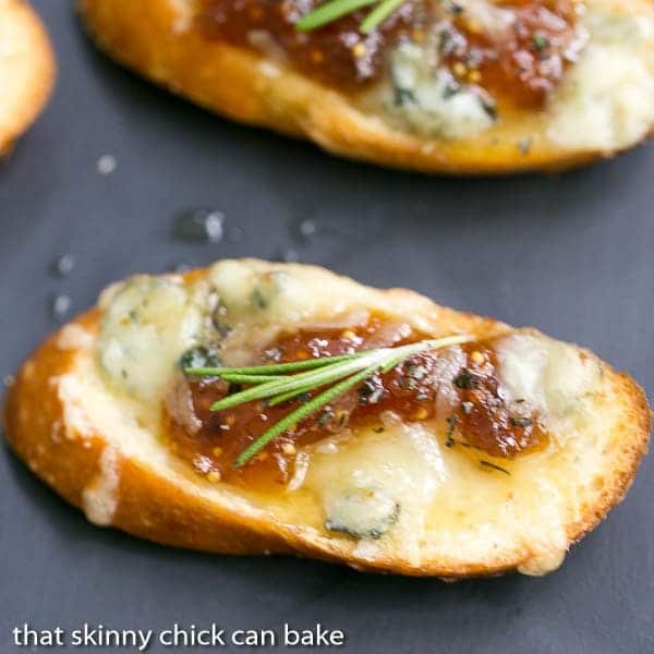 Fig Gruyere Crostini garnished with rosemary on a slate platter