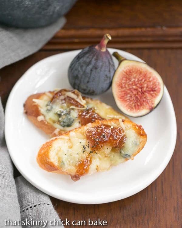 Fig Gruyere Crostini  on a white appetizer plate with fresh figs.