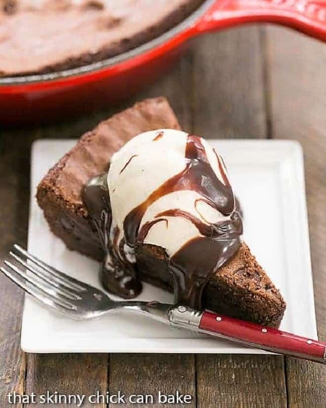 Fudgy Skillet Brownies slice on a square white plate with a red handled fork.