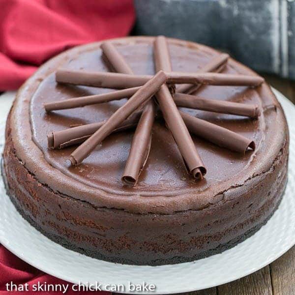 Triple Chocolate Cheesecake on a white ceramic plate topped with chocolate curls.